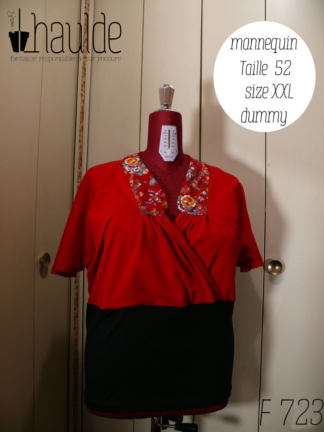 Haut coeur croisé à manches courtes en jersey rouge qui blouse jusqu'à la taille et jersey noir moulant de la taille aux hanches Le col est garni de tissu rouge imprimé fleurs et papillons d'inspiration Est asiatique, soulignés de doré. Vu de face sur un mannequin de couture réglé en taille 52