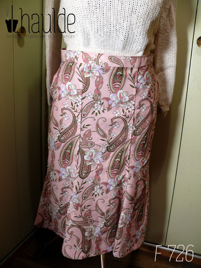 Jupe mi longue à quilles (pans supplémentaires en bas, qui froufroutent quand on marche) en sergé de viscose rose pâle imprimé paisley et fleurs dans les tons roses et gris, soulignés de vert foncé, rehaussés de blanc. Vue de face sur un mannequin de couture réglé en 44 La ceinture est un peu large.