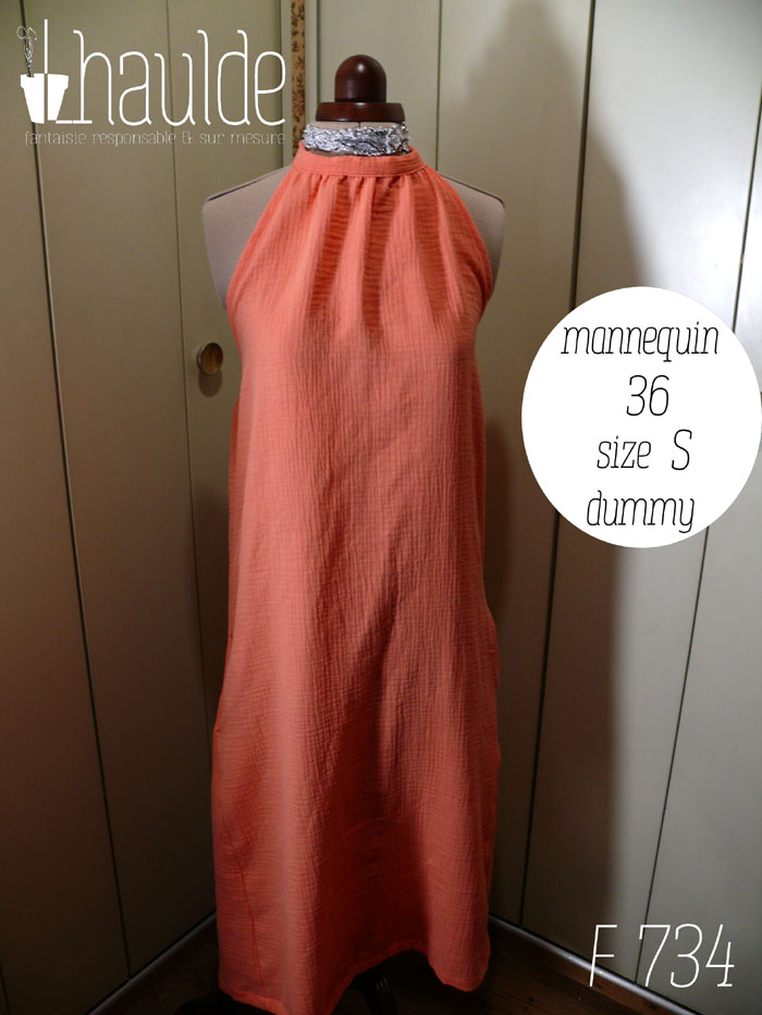 Robe mi longue dos nu nouée autour du cou, sans décolleté, en double gaze corail clair un peu orangé. Vue de face sur un mannequin de couture réglé en taille 36/S