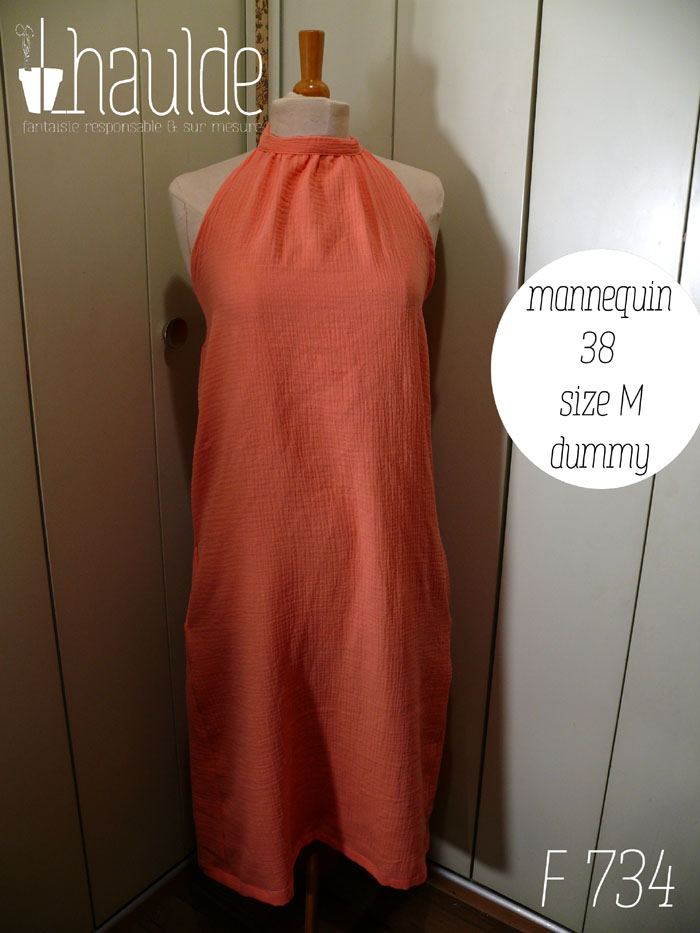 Robe mi longue dos nu nouée autour du cou, sans décolleté, en double gaze corail clair un peu orangé. Vue de face sur un mannequin de couture réglé en taille 38/M