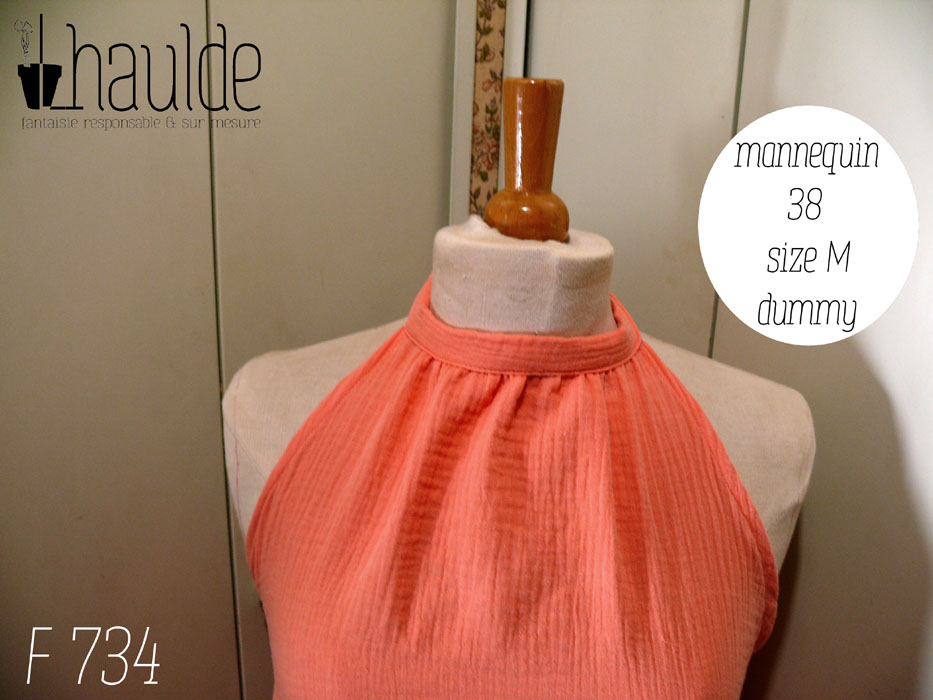Vue de détail du haut de la robe Robe mi longue dos nu nouée autour du cou, sans décolleté, en double gaze corail clair un peu orangé. Vue de face sur un mannequin de couture réglé en taille 38/M