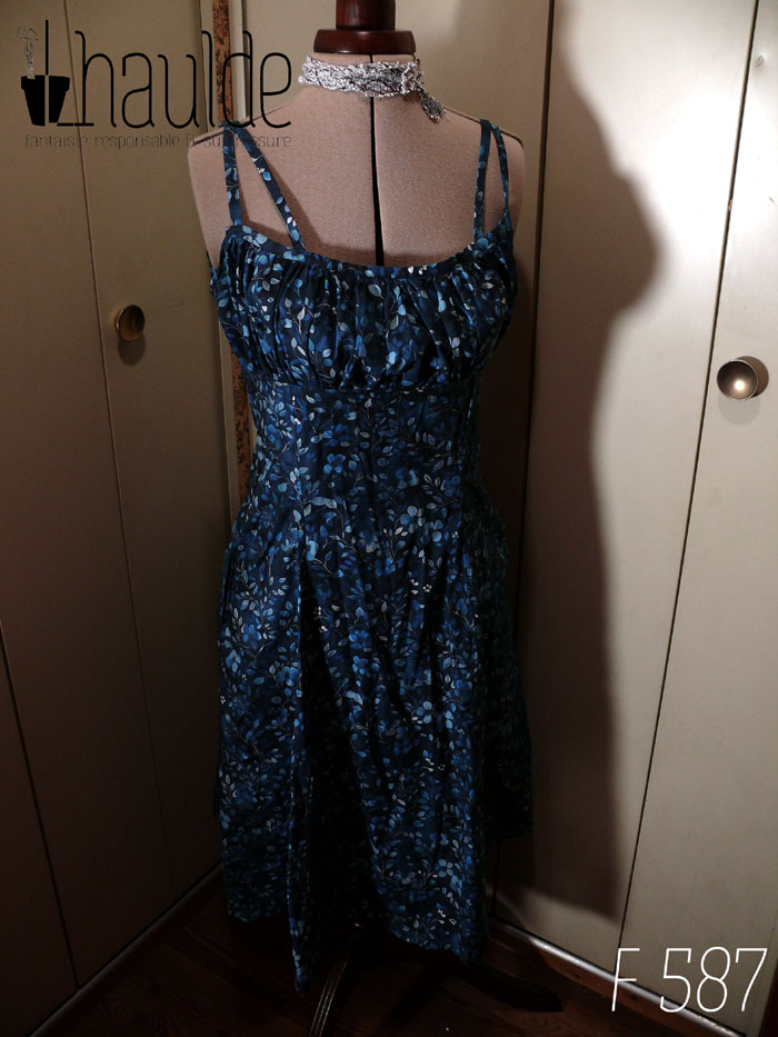 Robe mi-longue avec deux paires de fines bretelles réglables, buste plissé, taille ajustée, jupe ample, en popeline bleu nuit imprimé petite fleurs et végétaux délicats en dégradé de bleu jean Vue de face sur un mannequin de couture