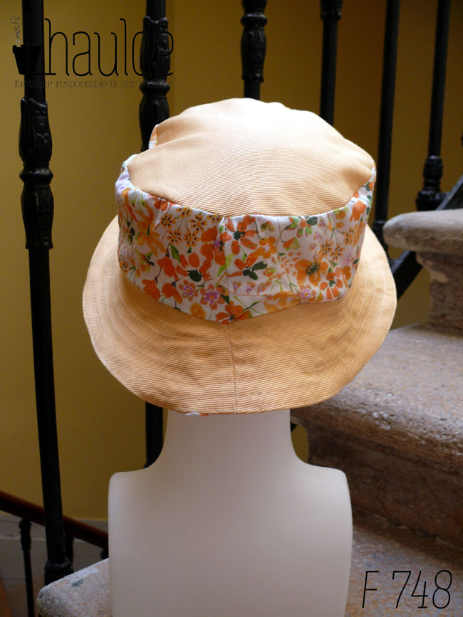 Bob court en sergé jaune pâle et tissu blanc imprimé de fleurs oranges et roses Bord jaune, bande centrale fleurs, sommet jaune, vu de dos sur une tête de mannequin Sur l'envers les bandes sont inversées