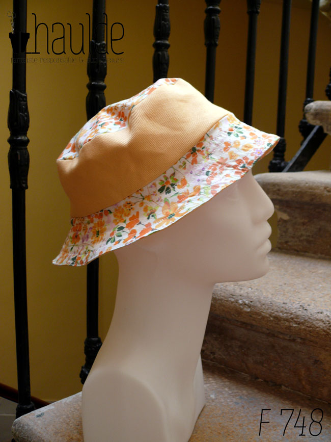 Bob court en sergé jaune pâle et tissu blanc imprimé de fleurs oranges et roses Bord fleurs, bande centrale jaune, sommet fleurs, vu de profil sur une tête de mannequin Sur l'envers les bandes sont inversées