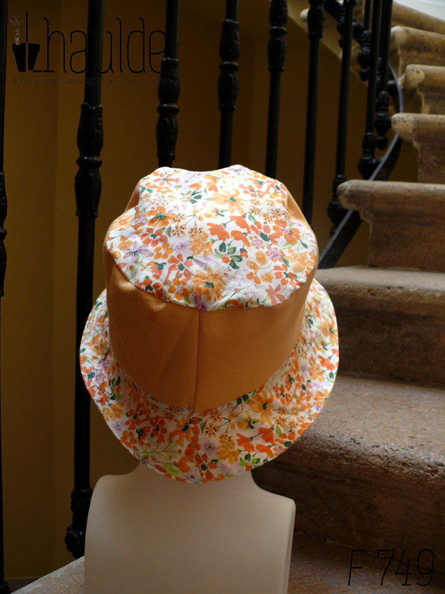 Bob classique en sergé jaune pâle et tissu blanc imprimé de fleurs oranges et roses Bord fleurs, bande centrale jaune, sommet fleurs, vu de dos sur une tête de mannequin Sur l'envers les bandes sont inversées