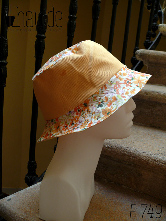 Bob classique en sergé jaune pâle et tissu blanc imprimé de fleurs oranges et roses Bord fleurs, bande centrale jaune, sommet fleurs, vu de profil sur une tête de mannequin Sur l'envers les bandes sont inversées