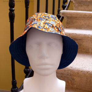 Bob en tissu imprimé orange, motifs végétaux stylisés bleus roi et blancs L'envers est en sergé bleu roi Vu de face sur une tête de mannequin