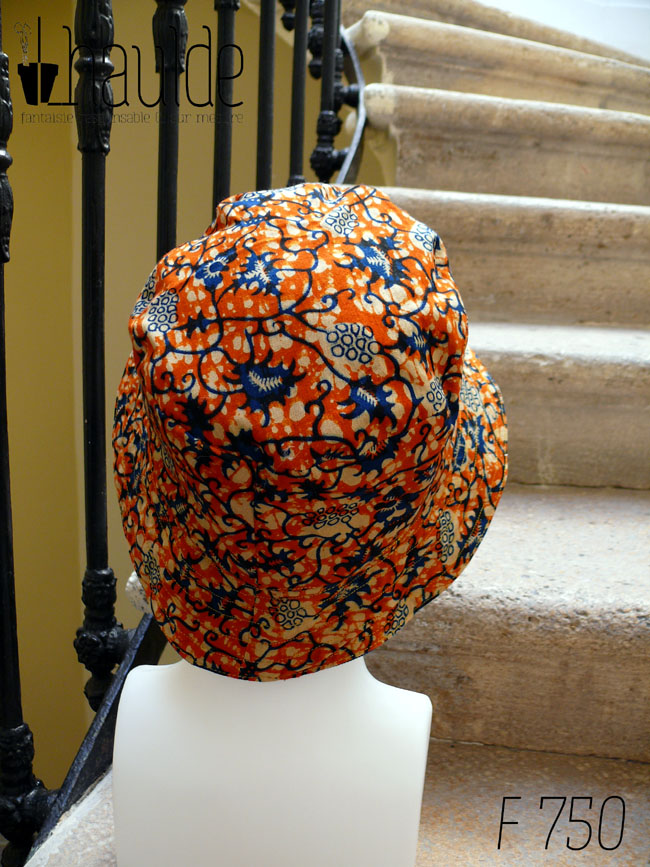 Bob en tissu imprimé orange, motifs végétaux stylisés bleus roi et blancs L'envers est en sergé bleu roi Vu de dos sur une tête de mannequin