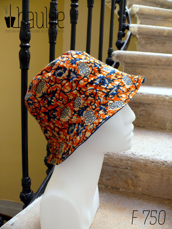 Bob en tissu imprimé orange, motifs végétaux stylisés bleus roi et blancs L'envers est en sergé bleu roi Vu de profil sur une tête de mannequin