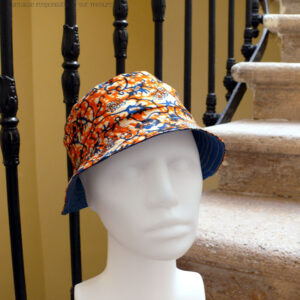 Bob court en tissu imprimé orange, motifs végétaux stylisés bleus roi et blancs L'envers est en sergé bleu roi Vu de trois quarts face sur une tête de mannequin