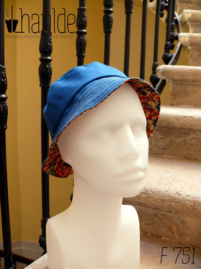 Bob court en tissu imprimé orange, motifs végétaux stylisés bleus roi et blancs L'envers est en sergé bleu roi Vu côté envers uni sur une tête de mannequin