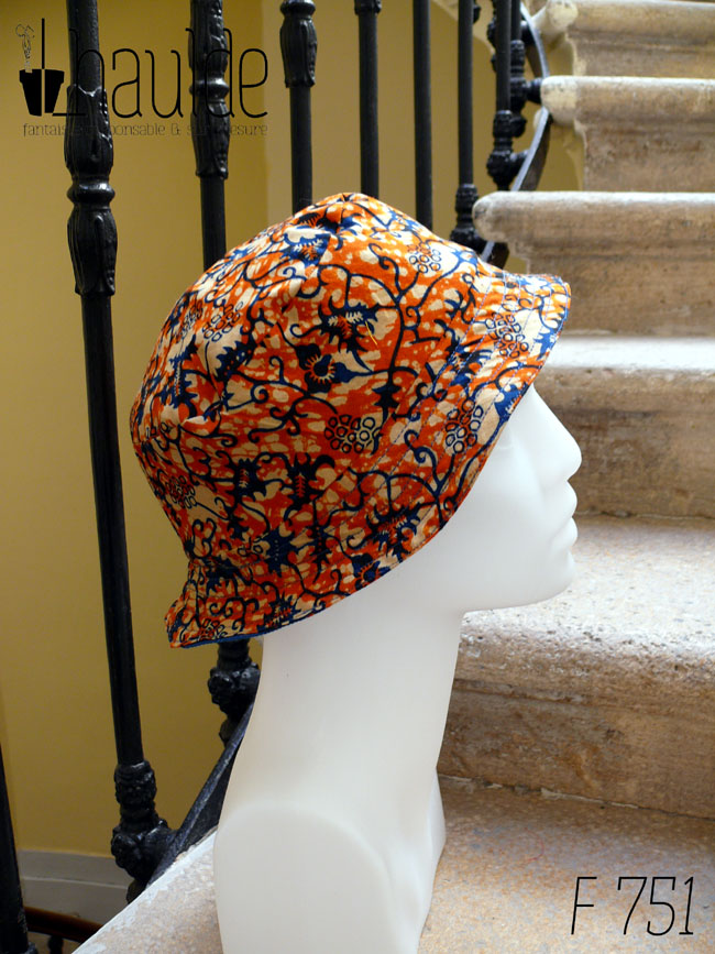Bob court en tissu imprimé orange, motifs végétaux stylisés bleus roi et blancs L'envers est en sergé bleu roi Vu de profil sur une tête de mannequin
