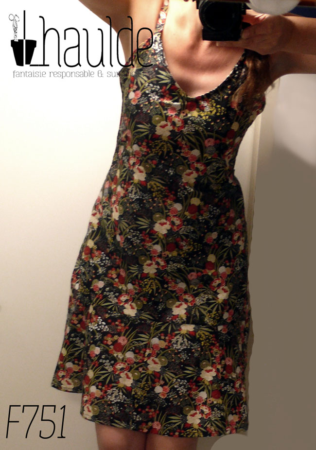 Robe courte décolletée à bretelles fines en coton noir imprimé de bouquets de roses et de dahlias stylisés blancs et rouges avec de grandes gerbes de feuilles longues et pointues kakis Vue portée, de face, selfie dans un miroir, l'image est un peu floue