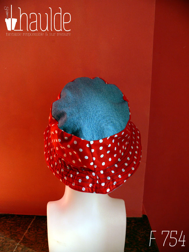 Bob court en tissu rouge à pois blanc et jean bleu clair. Réversible, vu côté rouge à pois, le dessus du chapeau est en jean. De dos sur une tête de mannequin