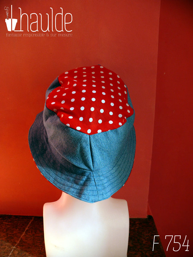Bob court en jean bleu clair et tissu rouge à pois blanc, réversible, vu côté jean (le dessus du chapeau est en tissu rouge à pois) de dos sur une tête de mannequin