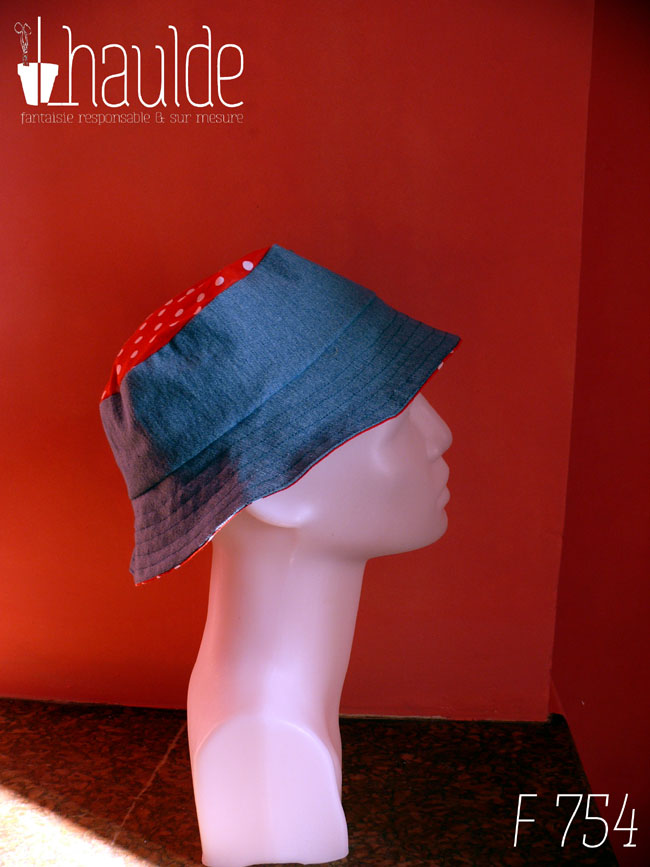 Bob court en jean bleu clair et tissu rouge à pois blanc, réversible, vu côté jean (le dessus du chapeau est en tissu rouge à pois) de profil sur une tête de mannequin