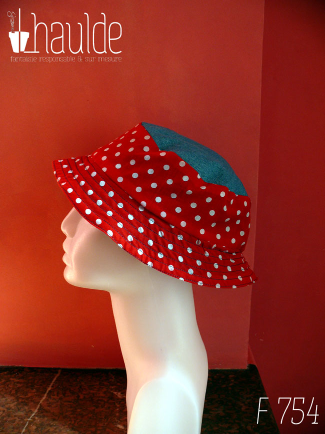 Bob court en tissu rouge à pois blanc et jean bleu clair. Réversible, vu côté rouge à pois, le dessus du chapeau est en jean. De profil sur une tête de mannequin