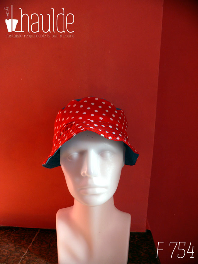 Bob court en tissu rouge à pois blanc et jean bleu clair. Réversible, vu côté rouge à pois, le dessus du chapeau est en jean. De face sur une tête de mannequin