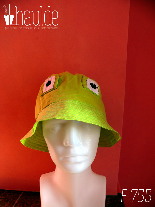 Bob grenouille avec des yeux en tissu cousus dessus. Le haut du bob est en tissu vert anis, le rebord dans un tissu un peu plus clair vert acide avec des lignes de losanges un peu plus foncées Vu de face sur une tête de mannequin