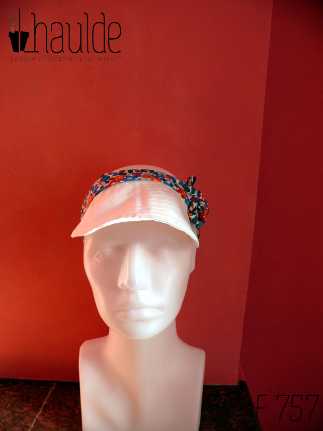 Visière en coton blanc surpiqué nouée sur le dessus de la tête avec des rubans blancs imprimés de fleurs multicolores à dominante rouge et bleu Vue de face sur une tête de mannequin