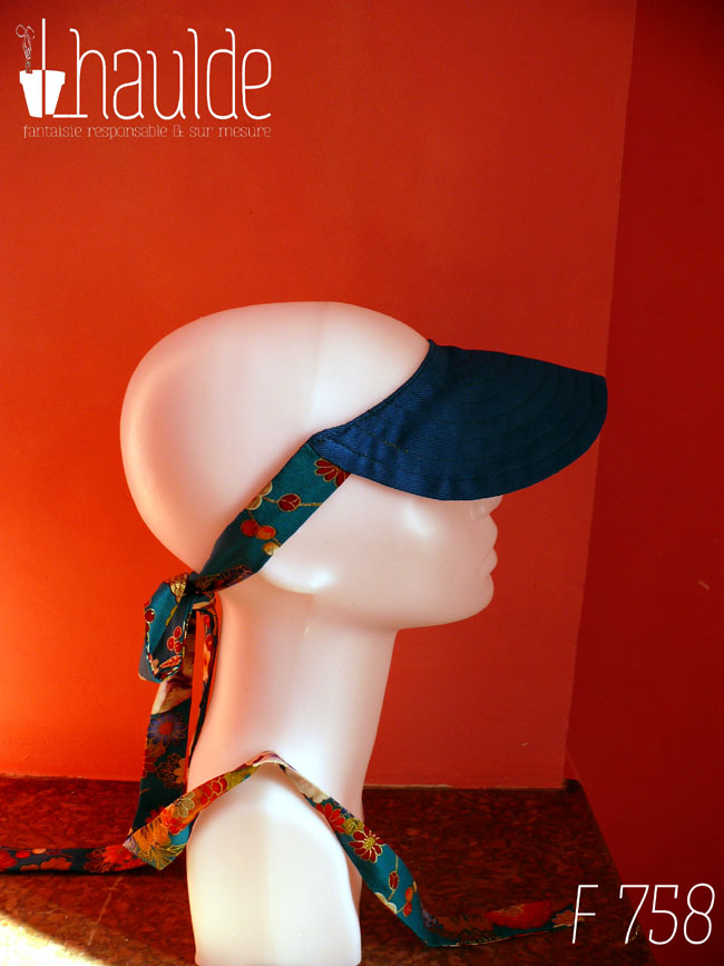 Visière bleu foncé nouée à l'arrière de la tête par des rubans bleu paon imprimé fleuri d'esthétique chinoise, dahlias et autres fleurs multicolores rehaussées de doré Vue de profil sur une tête de mannequin