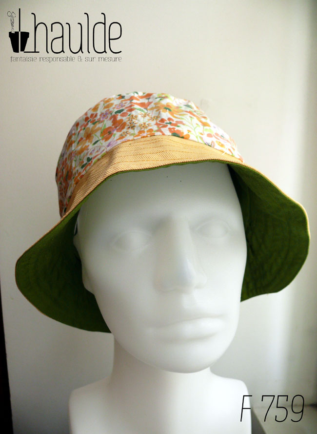 Bob classique en sergé jaune pâle et tissu blanc imprimé de fleurs oranges et roses Bord jaune, bande centrale fleurs, sommet jaune, vu de face sur une tête de mannequin Sur l'envers c'est un bob grenouille verte