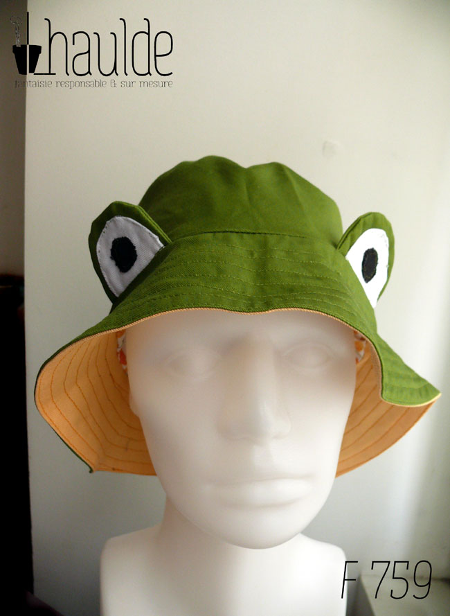 Bob grenouille vert avec des yeux en tissu cousus dessus L'intérieur est jaune Vu de face sur une tête de mannequin