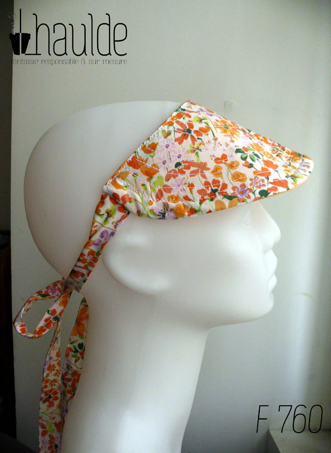 Visière à nouer en tissu blanc imprimé de fleurs oranges et roses, les brides sont également en tissu imprimé Vue de profil sur une tête de mannequin