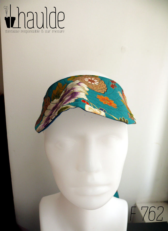 Visière à nouer en tissu bleu paon imprimé fleuri d'esthétique chinoise, dahlias et autres fleurs multicolores rehaussées de doré Vue de face sur une tête de mannequin