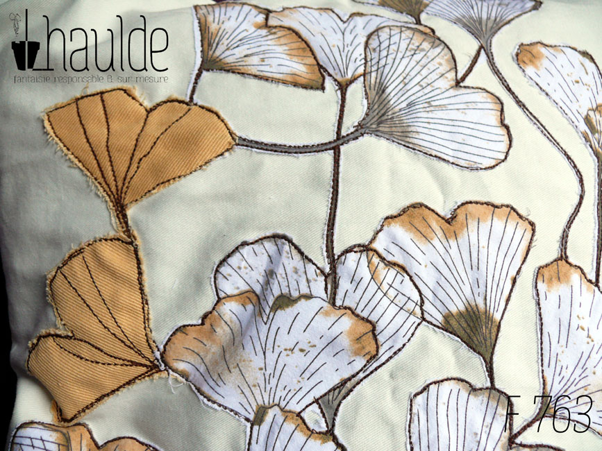 Housse de coussin blanc cassé avec des appliqués en tissu imprimé feuilles de ginkgo translucide et d'appliqués en forme de feuille de ginkgo en sergé jaune orangé surpiqué pour faire les nervures Vue de détail des appliqués