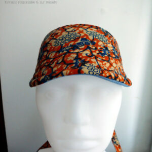 Visière à nouer en coton orange imprimé de motifs végétaux stylisés bleu et écru Vue de face sur une tête de mannequin