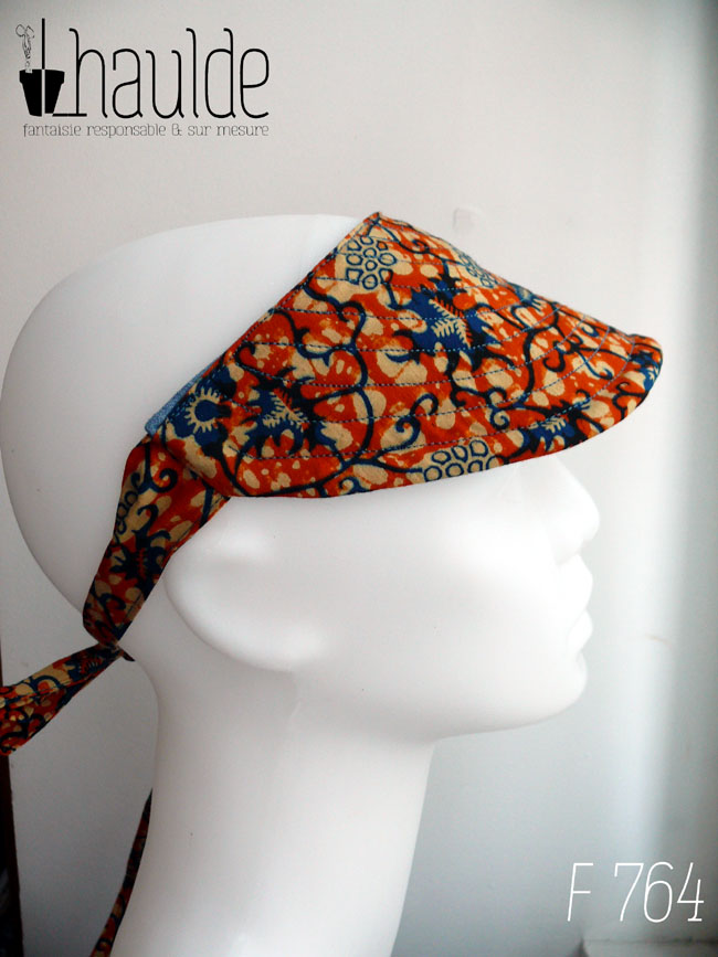 Visière à nouer en coton orange imprimé de motifs végétaux stylisés bleu et écru Vue de profil sur une tête de mannequin