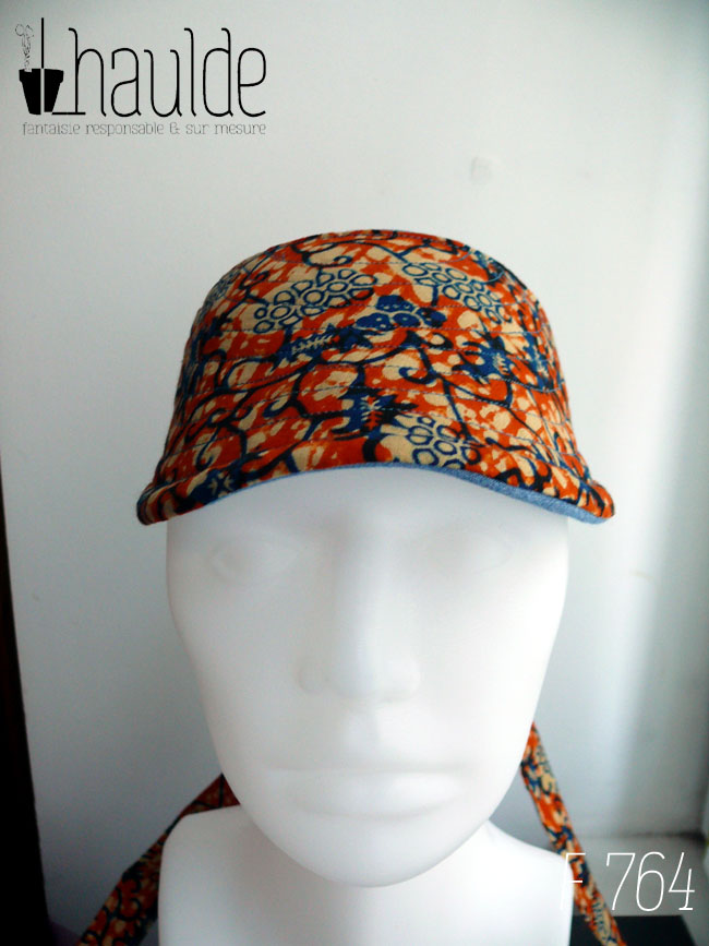 Visière à nouer en coton orange imprimé de motifs végétaux stylisés bleu et écru Vue de face sur une tête de mannequin