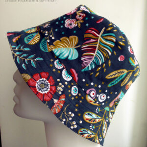 Bob en toile bleu marine imprimée de motifs fleuris et feuillus dans les tons roses, bleu turquoise et rouge Vu de profil sur une tête de mannequin