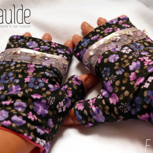 Mitaines en jersey noir imprimé de petites fleurs violettes, le pouce est couvert et au niveau des phalanges les mitaines sont garnies d'un galon d'organza transparent, garni d'un ruban rose pâle et de sequins ronds maintenus par des perles de rocailles Vue de la paire portée