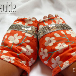 Mitaines en jersey corail imprimé de fleurs de cerisier blanches stylisées, avec des tiges turquoises Un galon de sequins argentés décore les mitaines au niveau des phalanges Vue de la paire portée