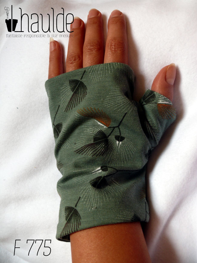 Mitaines en jersey vert céladon imprimé de motifs végétaux en forme de feuilles de palmes stylisées et aérées. Le pouce est couvert Vue d'une mitaine portée, côté dos de la main