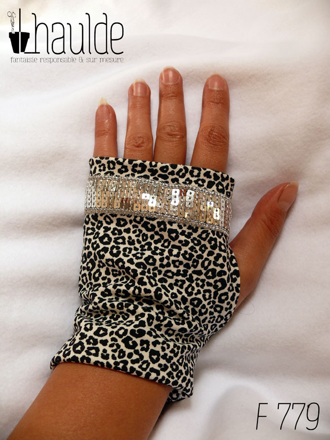 Paire de mitaines en jersey écru imprimé de petits motifs léopard noir. Avec au niveau des phalanges un galon de sequins carrés argentés sur 5 rangs vue de dessus côté dos de la main, elles vont de la première phalange jusqu'au poignet