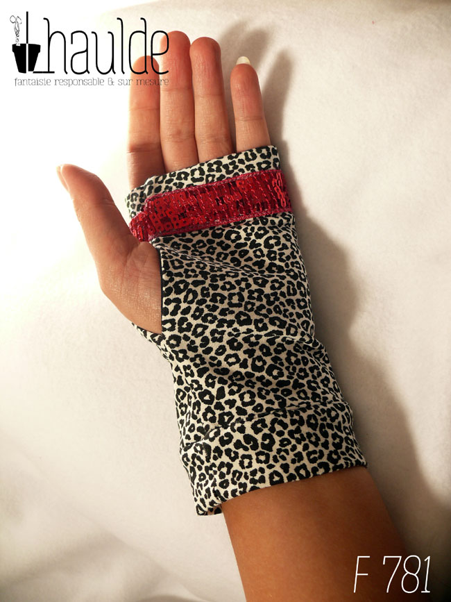 Paire de mitaines en jersey écru imprimé de petits motifs léopard noir. Avec au niveau des phalanges un galon de sequins carrés rouge fraises sur 5 rangs vue de dessus côté paume