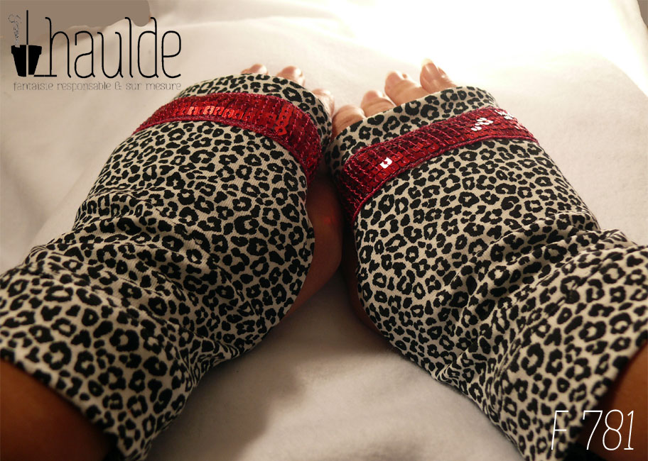 Paire de mitaines en jersey écru imprimé de petits motifs léopard noir. Avec au niveau des phalanges un galon de sequins carrés rouge fraises sur 5 rangs Vue de la paire portée