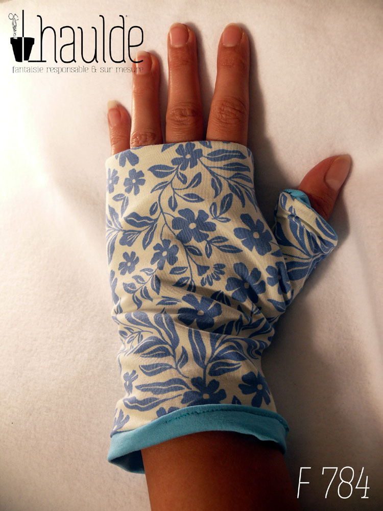Paire de mitaines pouce long en jersey blanc imprimé de motifs floraux bleus en silhouette uni. Doublure en jersey bleu pastel qui ressort au niveau du poignet Vue d'une mitaine portée côté dos de la main