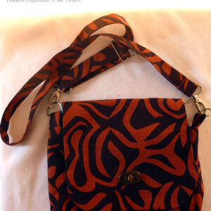 sac en tissu marron avec des motifs zèbre oranges foncés. Vu posé, son rabat fermé par son tourniquet couleur bronze Bandoulière réglable et amovible (sur mousquetons)