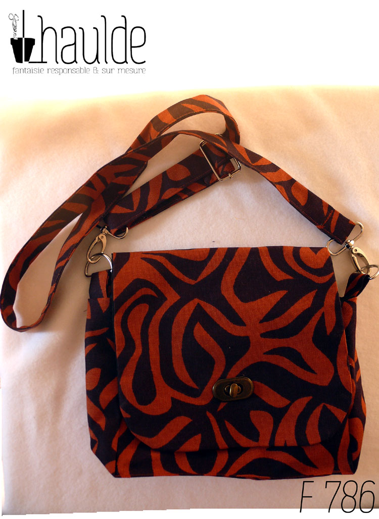 sac en tissu marron avec des motifs zèbre oranges foncés. Vu posé, son rabat fermé par son tourniquet couleur bronze Bandoulière réglable et amovible (sur mousquetons)
