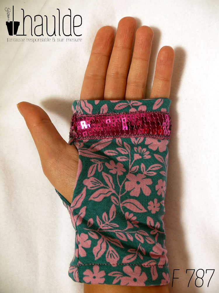 Paire de mitaines en jersey bleu pétrole imprimé de petites fleurs roses et décorée au niveau des phalanges d'un galon de sequins carrés fuchsia sur 5 rangs. vue de dessus côté paume de la main