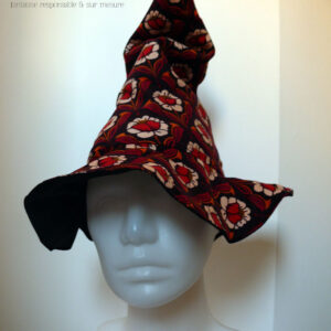 Chapeau de sorcière pointu en velours milleraies marron foncé imprimé de motifs floraux disposés de manière symétrique coeur de la fleur rouge, pétales blancs, feuilles orange et rouge foncé Vu de face sur une tête de mannequin