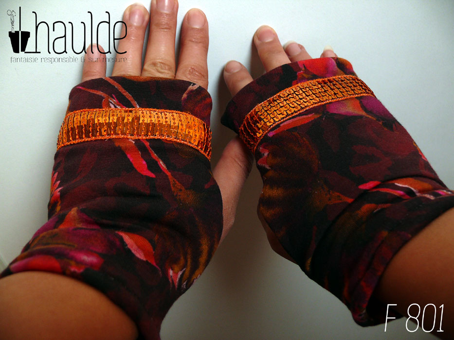 Paire de mitaines en jersey marron imprimé de motifs floraux délavés comme dans une aquarelle très humide, dans des tons chauds allant de l'ocre au fuchsia, garnie d'un galon de sequins carrés oranges sur cinq rangs Vue de la paire portée