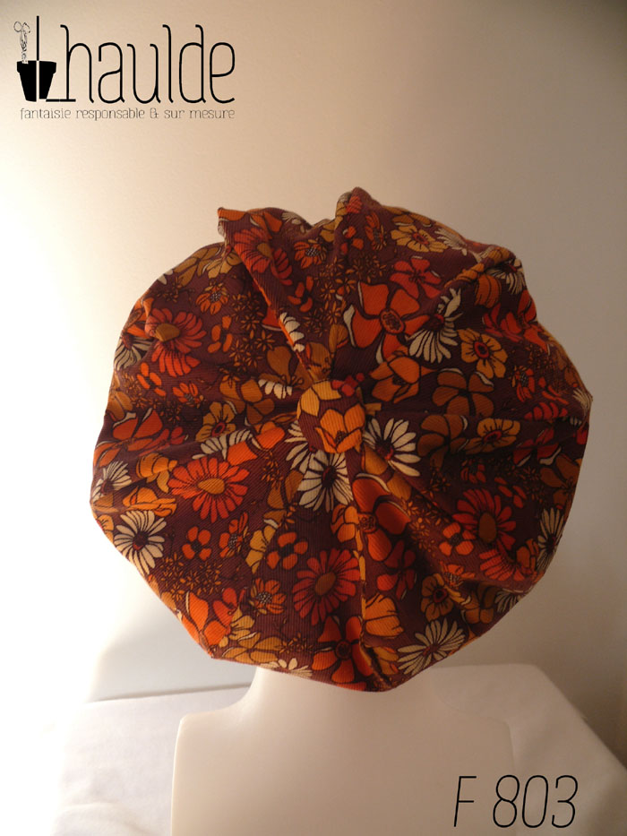 Casquette bouffante "gavroche" en milleraies marron imprimé de fleurs vintage (années 70) dans les tons oranges et ocre. Visière large Vue de dos, avec le bouton recouvert du même tissu au centre des 9 pans assemblés sur une tête de mannequin