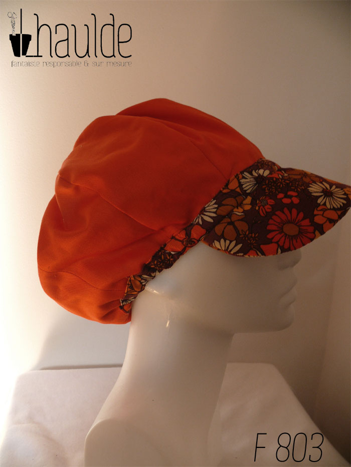 Casquette bouffante "gavroche" en milleraies marron imprimé de fleurs vintage (années 70) dans les tons oranges et ocre. Visière large Vue de profil côté doublure (sergé orange uni avec juste une bande en bas et la visière en tissu imprimé) sur une tête de mannequin