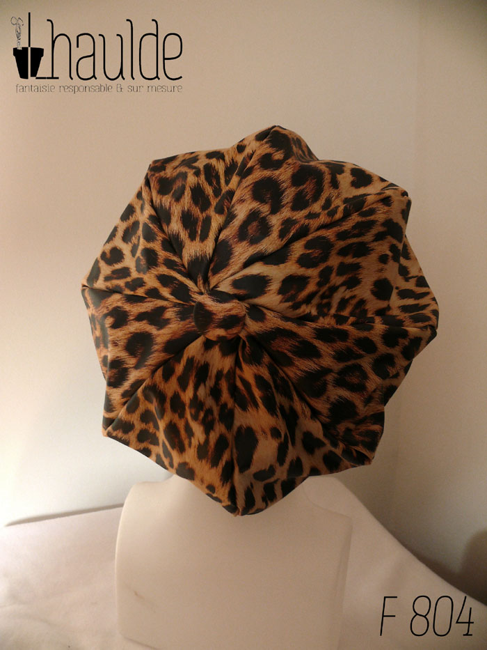 Casquette bouffante "gavroche" en simili cuir beige imprimé de motif léopard assez réaliste (les poils sont un peu dessinés) Visière large Vue de dos, avec le bouton recouvert du même tissu au centre des 8 pans assemblés sur une tête de mannequin